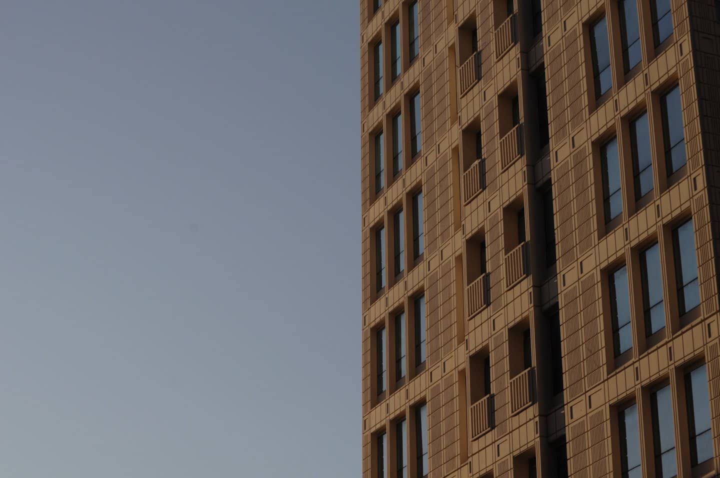 Moderno edificio a più piani con balconi contro un cielo limpido.