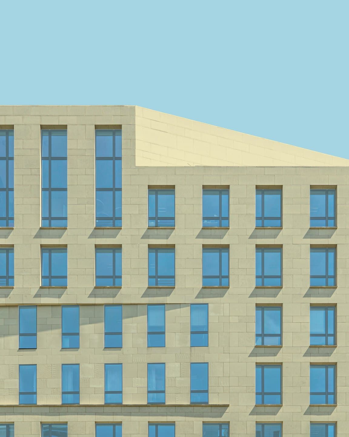 Facciata di un edificio moderno con finestre blu e pareti in pietra.
