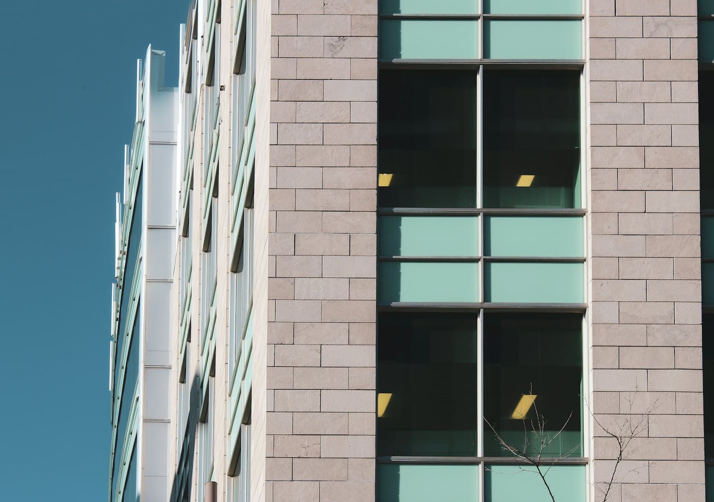Facciata di un moderno edificio per uffici con pannelli in pietra e finestre riflettenti.